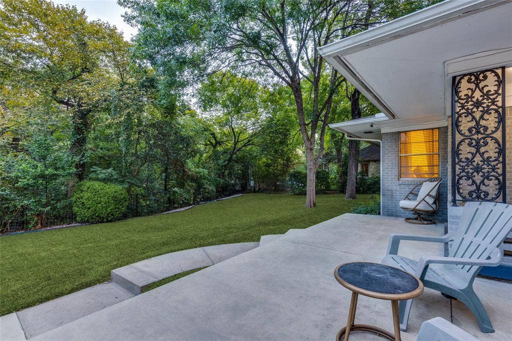 737 N Hampton Road, Dallas, TX 75208 Outdoor living beneath mature trees, with the creek and surrounding greenery close at hand.
