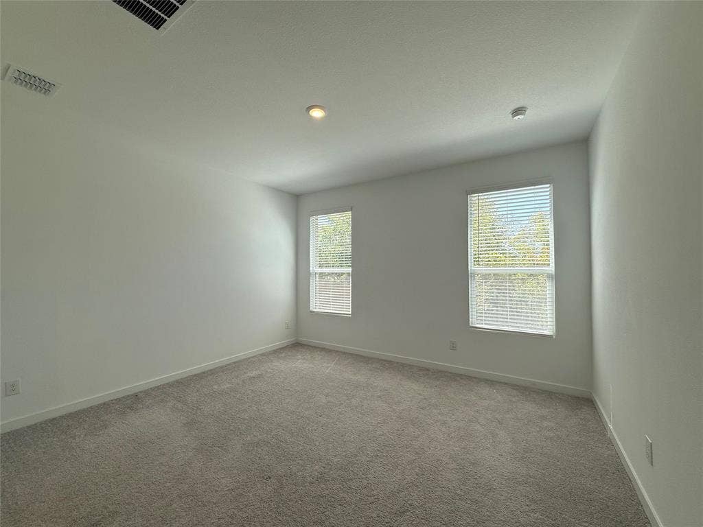Light-toned wall-to-wall carpeting, two windows with blinds, recessed ceiling lighting, and crisp white walls