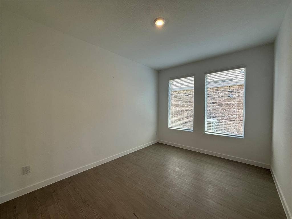 Recessed lighting, two large windows with blinds, light wood-finish flooring, and crisp white walls