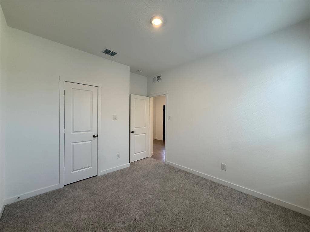 Plush grey carpeting, white interior doors, and a recessed ceiling light