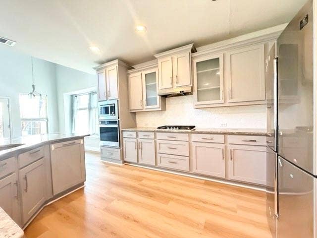 5609 Meritage Street, McKinney, TX 75070 Kitchen featuring light wood-finish flooring, light gray cabinetry, stainless steel appliances, and a white tile backsplash
