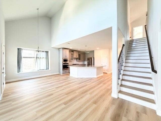 5609 Meritage Street, McKinney, TX 75070 Vaulted ceilings, wood-finish flooring, staircase with dark wood handrail, kitchen island with built-in appliances, stainless steel appliances