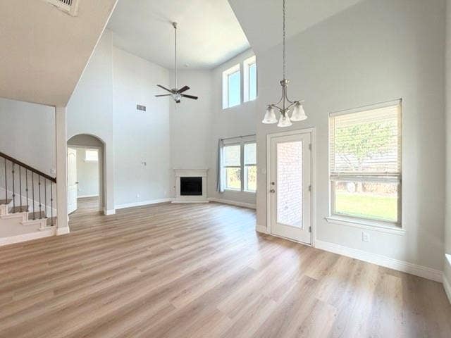 5609 Meritage Street, McKinney, TX 75070 Soaring ceilings with a chandelier, wood-finish flooring, a white mantel fireplace, and a staircase with wrought iron balusters