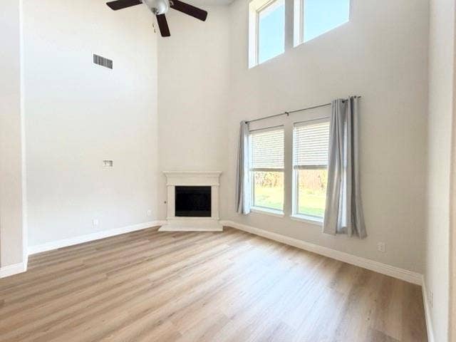 5609 Meritage Street, McKinney, TX 75070 Wood-finish flooring, corner fireplace with classic mantel, high ceilings, multiple windows, and a ceiling fan