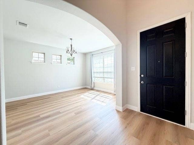 5609 Meritage Street, McKinney, TX 75070 Wood-finish flooring throughout, arched entryway, a black paneled door, and a multi-light chandelier