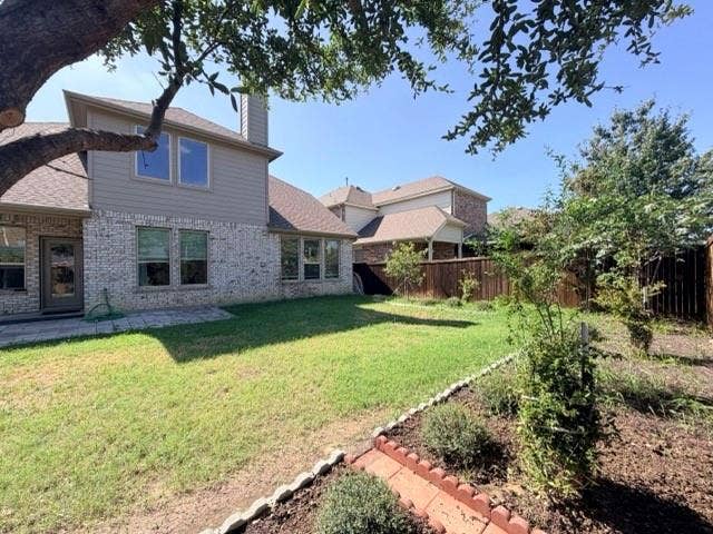 5609 Meritage Street, McKinney, TX 75070 Expansive backyard featuring a manicured lawn, brick and siding exterior, multiple windows, and a paved patio