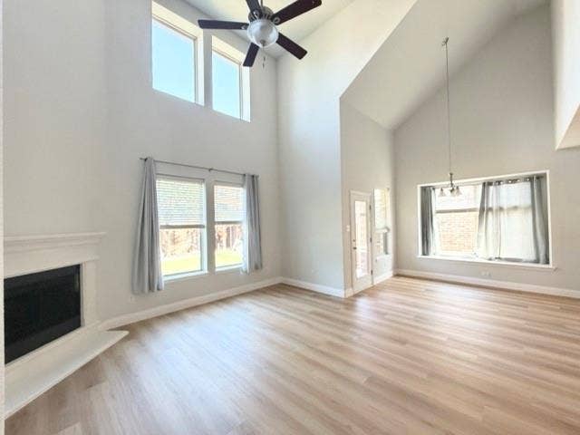 5609 Meritage Street, McKinney, TX 75070 Vaulted ceilings with a ceiling fan, light wood-finish flooring, white mantel fireplace, multiple windows, and a glass-paneled door