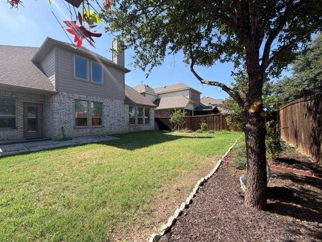 5609 Meritage Street, McKinney, TX 75070 Spacious backyard featuring a privacy fence, mature tree, and a brick and siding exterior