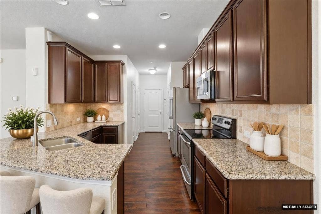 6529 Rutherford Road, Plano, TX 75023 The Kitchen offers wood flooring, granite counter-tops and a decorator tile backsplash (Virtually Staged).