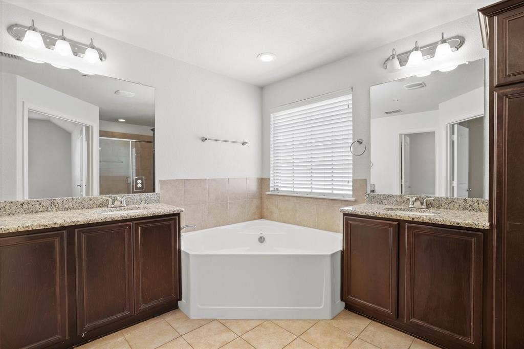 6529 Rutherford Road, Plano, TX 75023 The primary bath also ofers granite counter-tops, a separate tub and shower.