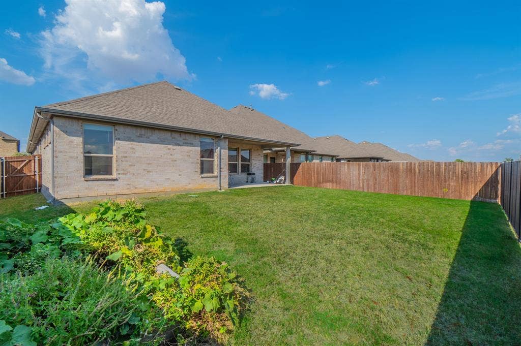 2041 St Andrews Way, Argyle, TX 76226 Expansive green lawn with a solid wood privacy fence, brick exterior, and covered patio
