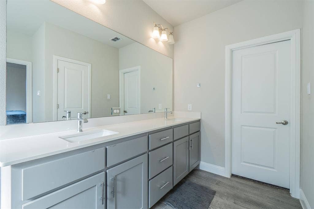 2041 St Andrews Way, Argyle, TX 76226 Dual vanity with rectangular undermount sinks, chrome faucets, light grey cabinetry, and white countertops