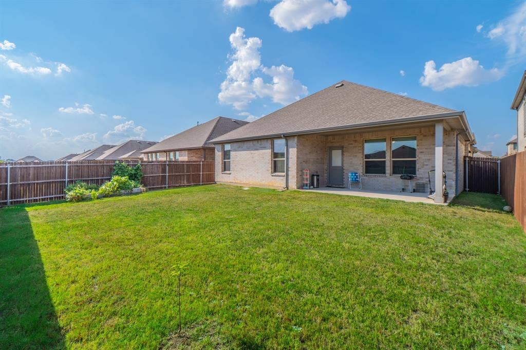 2041 St Andrews Way, Argyle, TX 76226 Expansive rear yard featuring green lawn, wood fencing, and a covered concrete patio