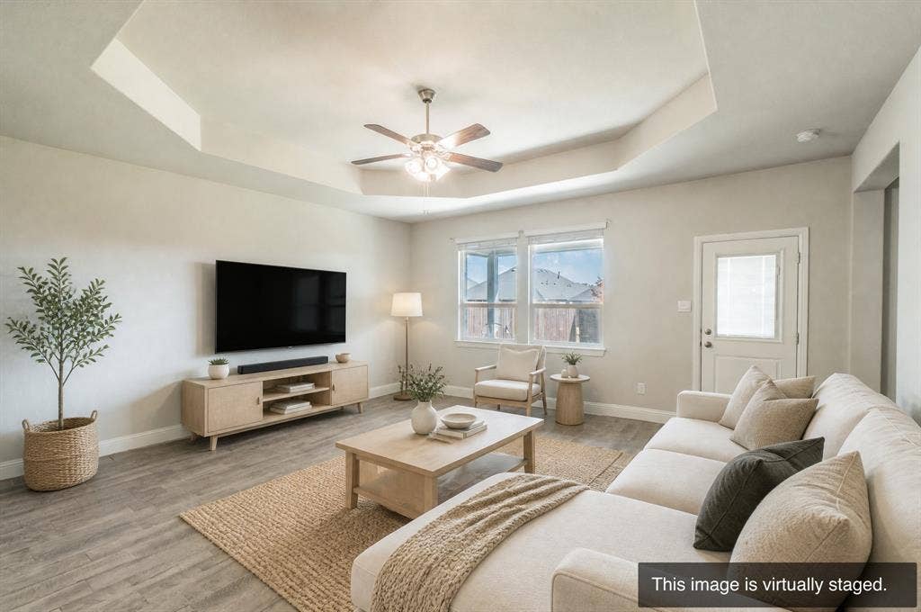 2041 St Andrews Way, Argyle, TX 76226 Tray ceiling with a ceiling fan, wood-finish flooring, multiple windows, and a rear exterior door