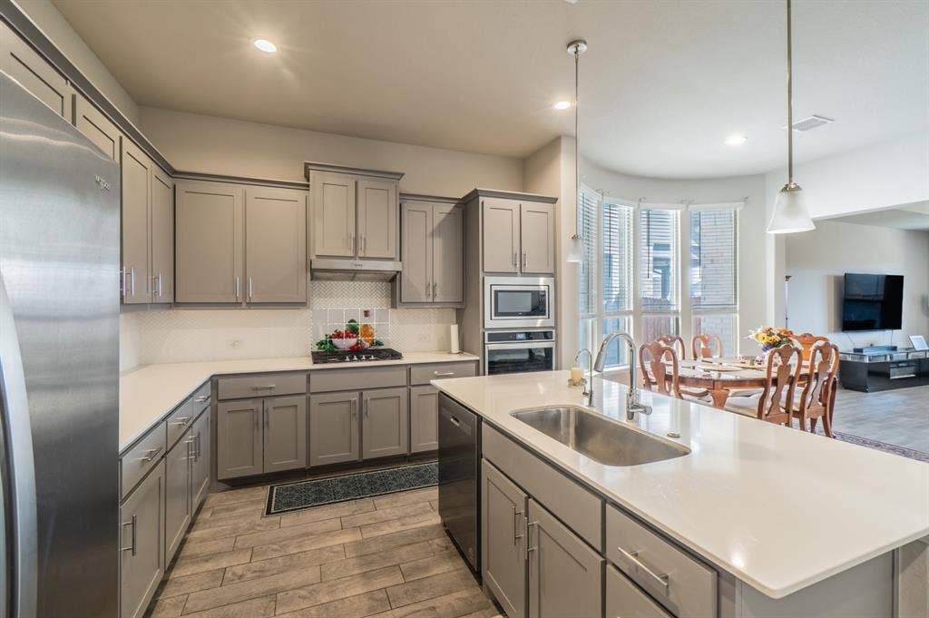 2041 St Andrews Way, Argyle, TX 76226 Kitchen featuring light wood-finish flooring, light gray cabinetry with brushed nickel hardware, light countertops, and stainless steel appliances