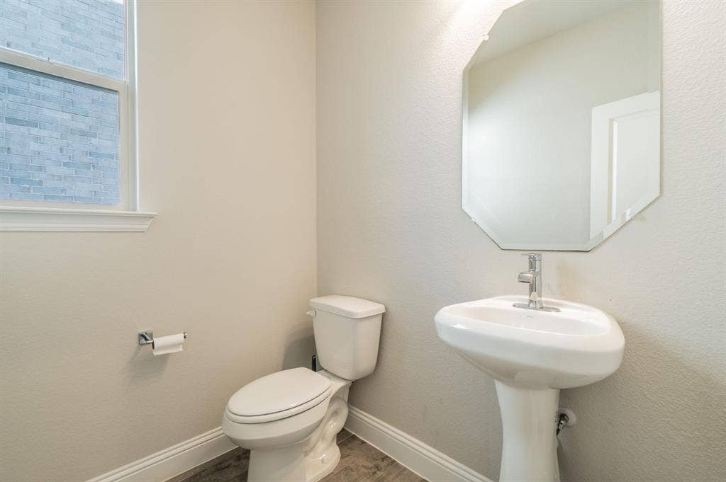 2041 St Andrews Way, Argyle, TX 76226 Pedestal sink with polished chrome faucet, octagonal mirror, toilet, and window with trim