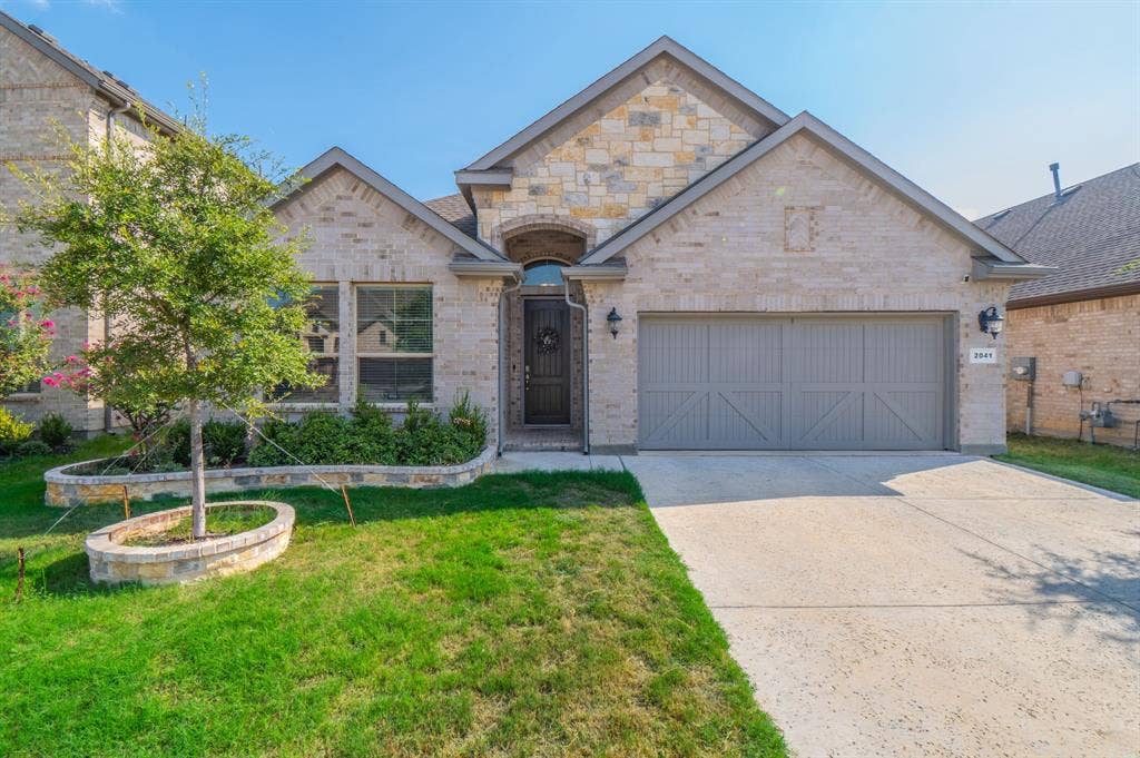 2041 St Andrews Way, Argyle, TX 76226 Stone and brick facade with an arched entry, a concrete driveway, and an attached garage with carriage-style doors
