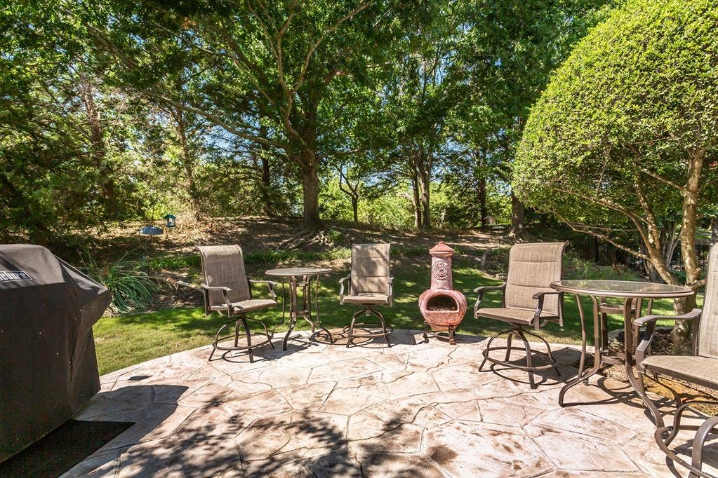 Expansive stamped concrete patio with surrounding mature trees and natural landscaping