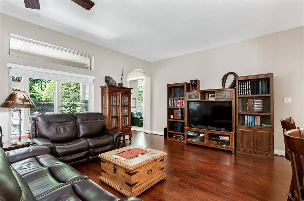 Wood-finish flooring, high ceilings, large windows with upper transom windows, ceiling fan, and arched doorway