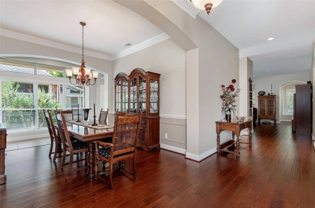 Hardwood flooring throughout, featuring crown molding, arched room openings, and a large window with transom detail