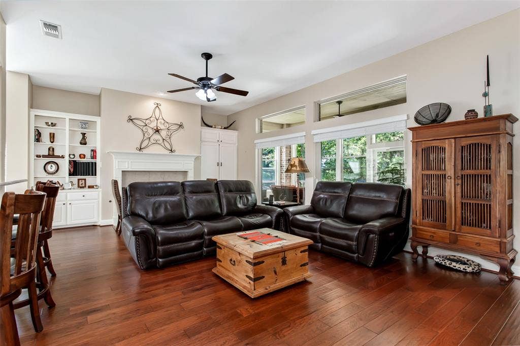 Hardwood flooring, built-in shelving, vaulted ceilings, a fireplace with a mantel, and transom windows