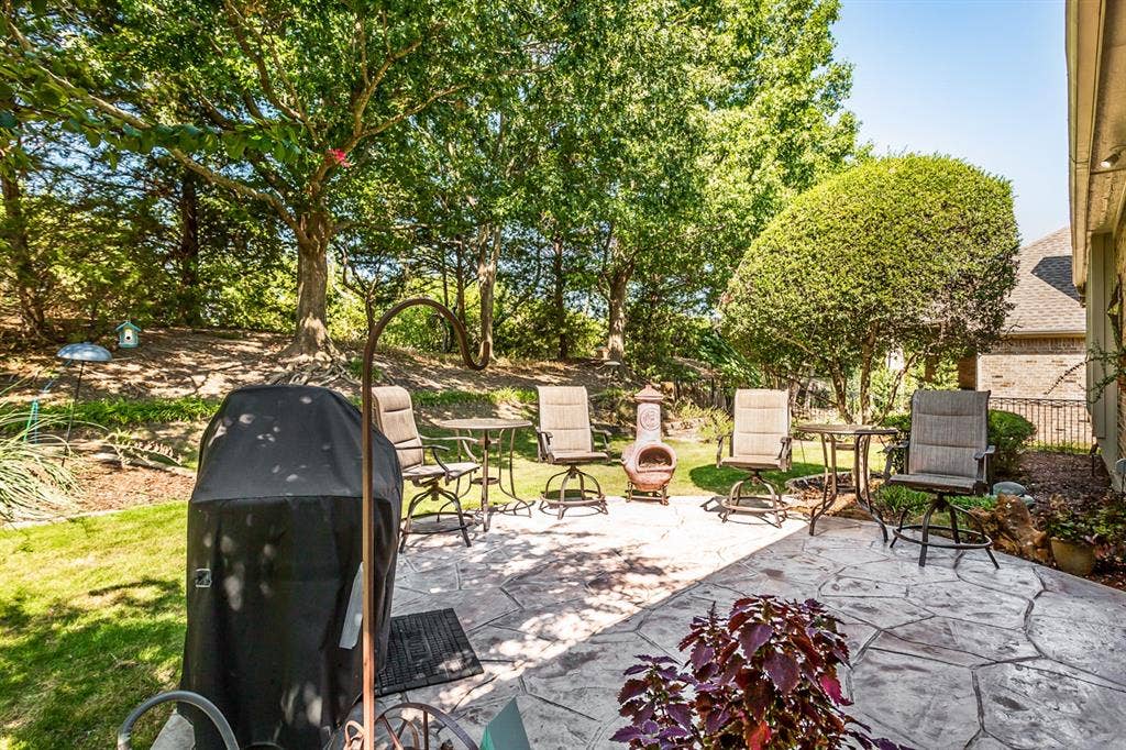 Stamped concrete patio with a landscaped perimeter and mature trees