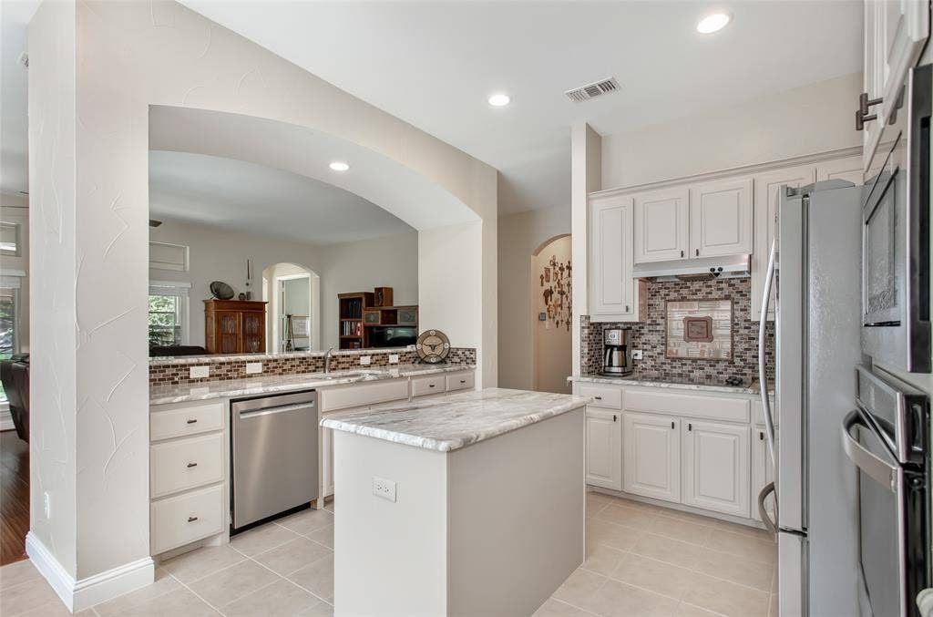 Kitchen featuring white cabinetry, light-toned countertops, a mosaic tile backsplash, stainless steel appliances, and recessed lighting