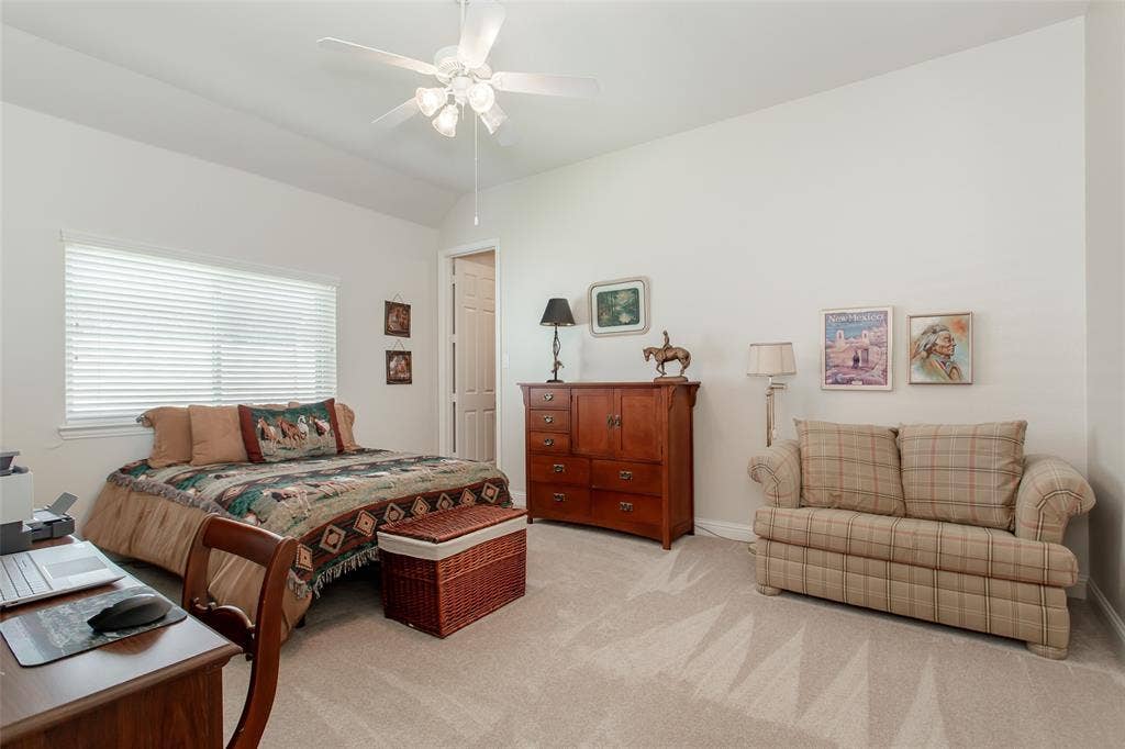 Neutral tone wall paint, carpeted flooring, window with blinds, ceiling fan with light fixture, and interior door