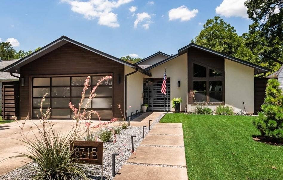 Modern architectural style featuring a light-toned exterior and dark wood-look siding