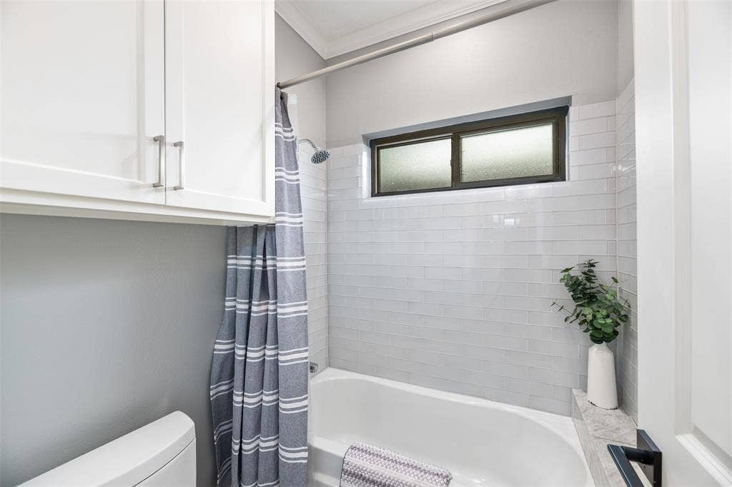 White subway tile shower surround, built-in bathtub, and horizontal window with privacy glass