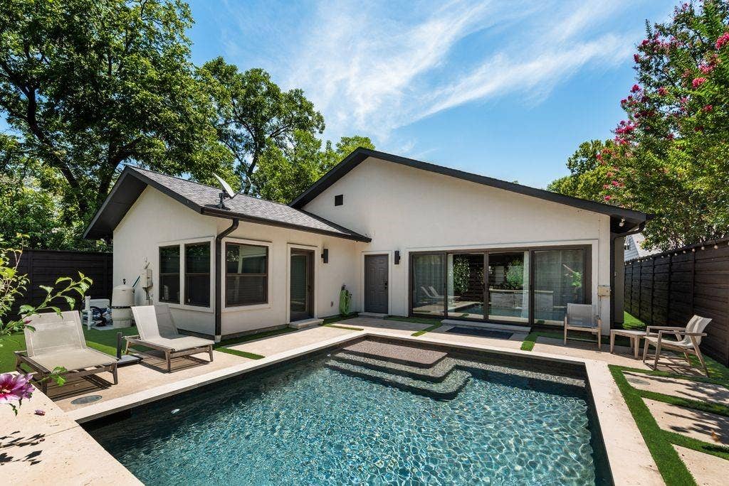 Private backyard featuring a dark-bottom pool with integrated steps, a surrounding patio, and a modern horizontal fence
