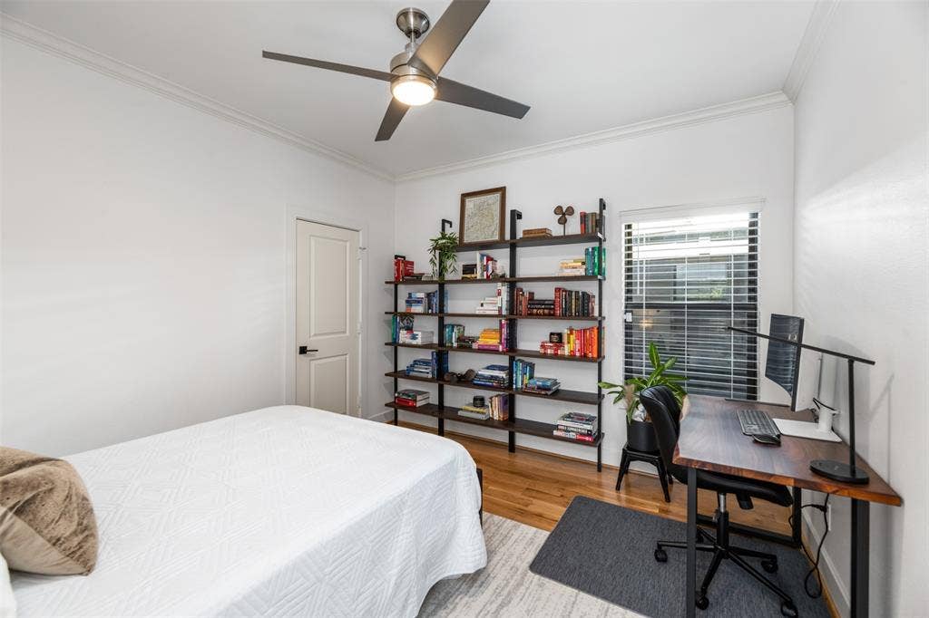 2nd bedroom Hardwood flooring, crown molding, ceiling fan with integrated lighting, built-in shelving, and a panel door with dark hardware