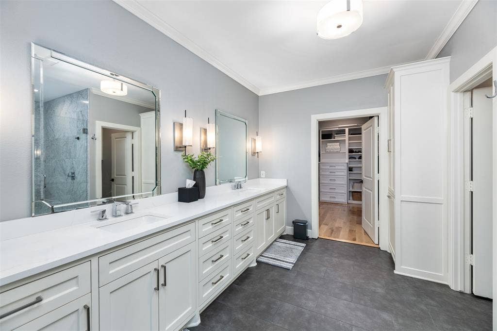 Dual vanity with white shaker cabinetry, white countertop, and dark rectangular floor tiles