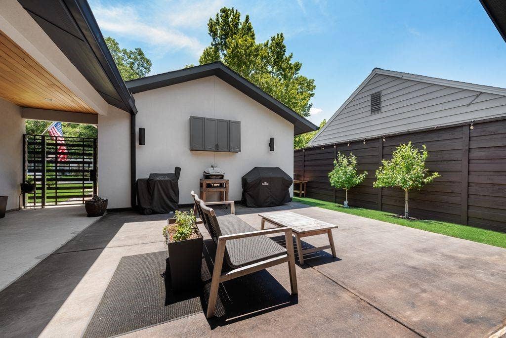 Patio featuring concrete surface, dark wood-finish fencing, wall-mounted cabinetry, and a metal security gate