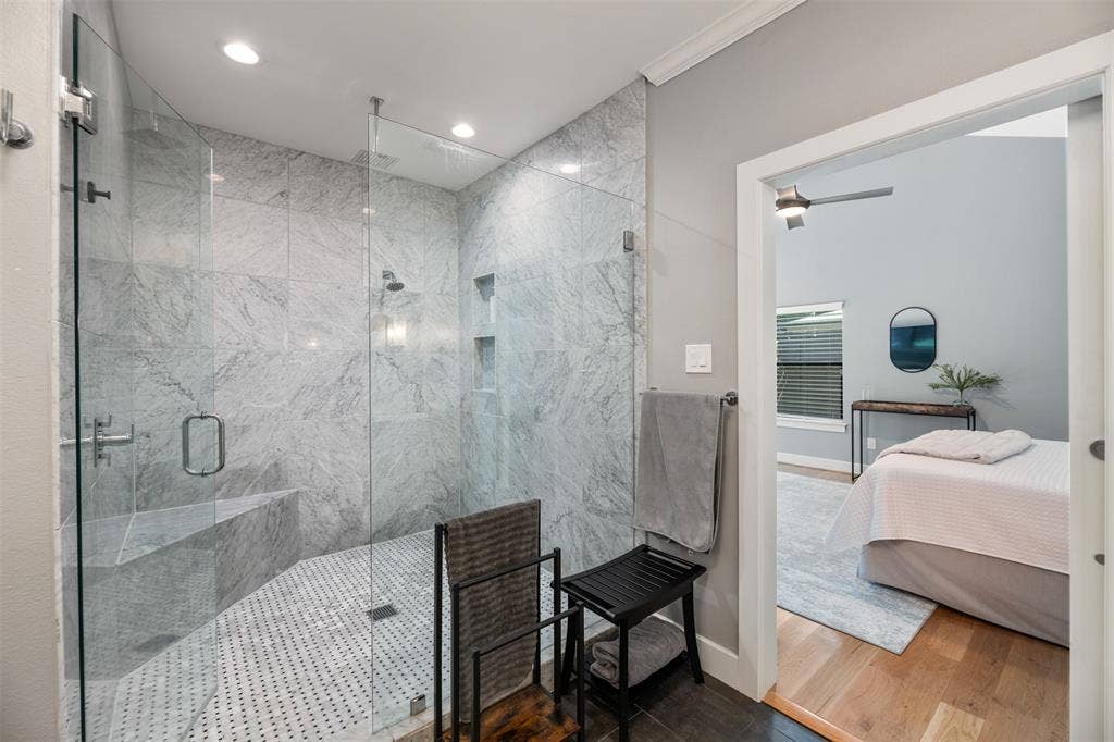 Walk-in shower with full-height stone-look tile, glass enclosure, built-in bench, and recessed lighting