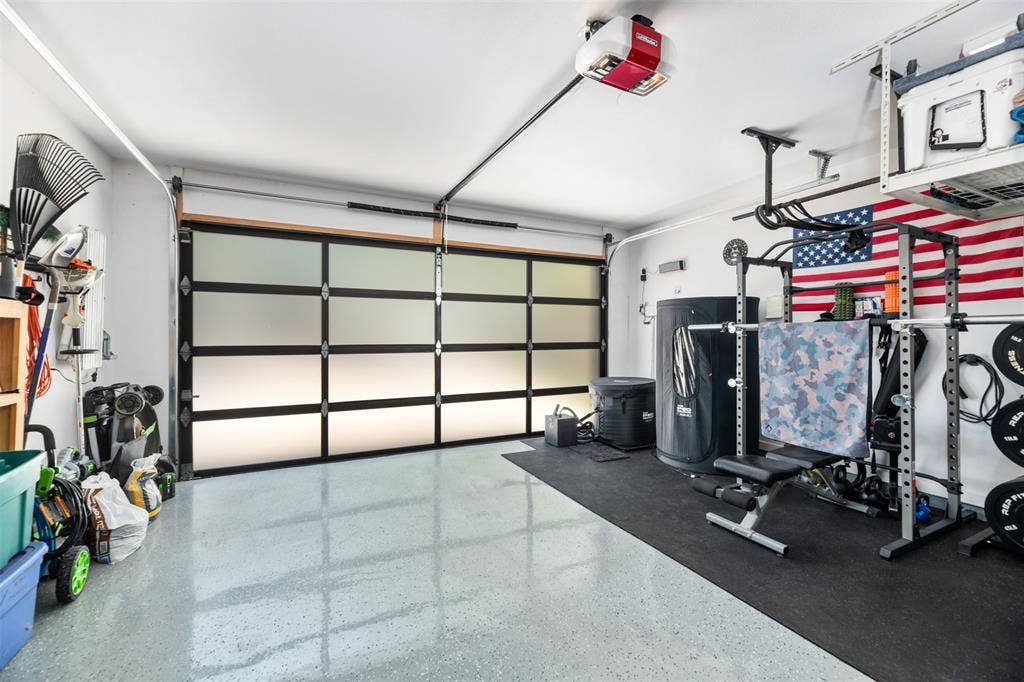 Translucent panel garage door with automatic opener, overhead storage racks, and light-toned epoxy flooring
