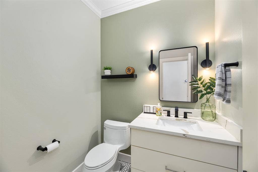 White vanity with a rectangular undermount sink and matte black faucet, framed mirror, and two wall-mounted sconces