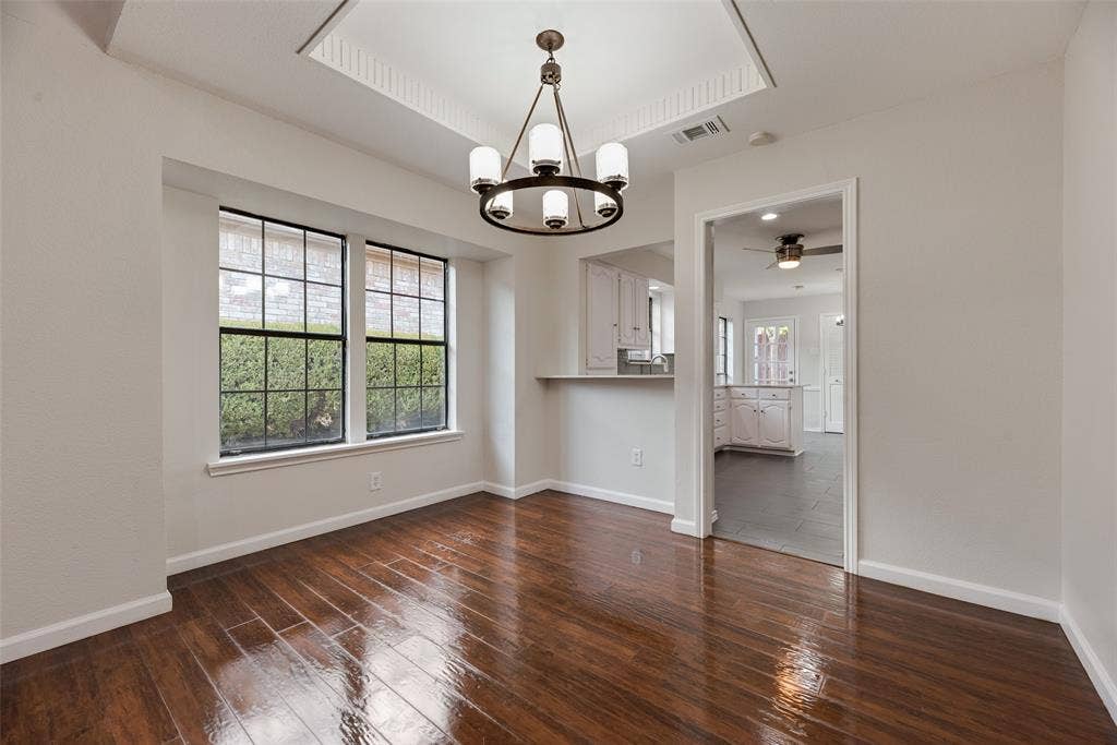 Hardwood flooring, recessed ceiling with crown molding, chandelier, and a breakfast bar