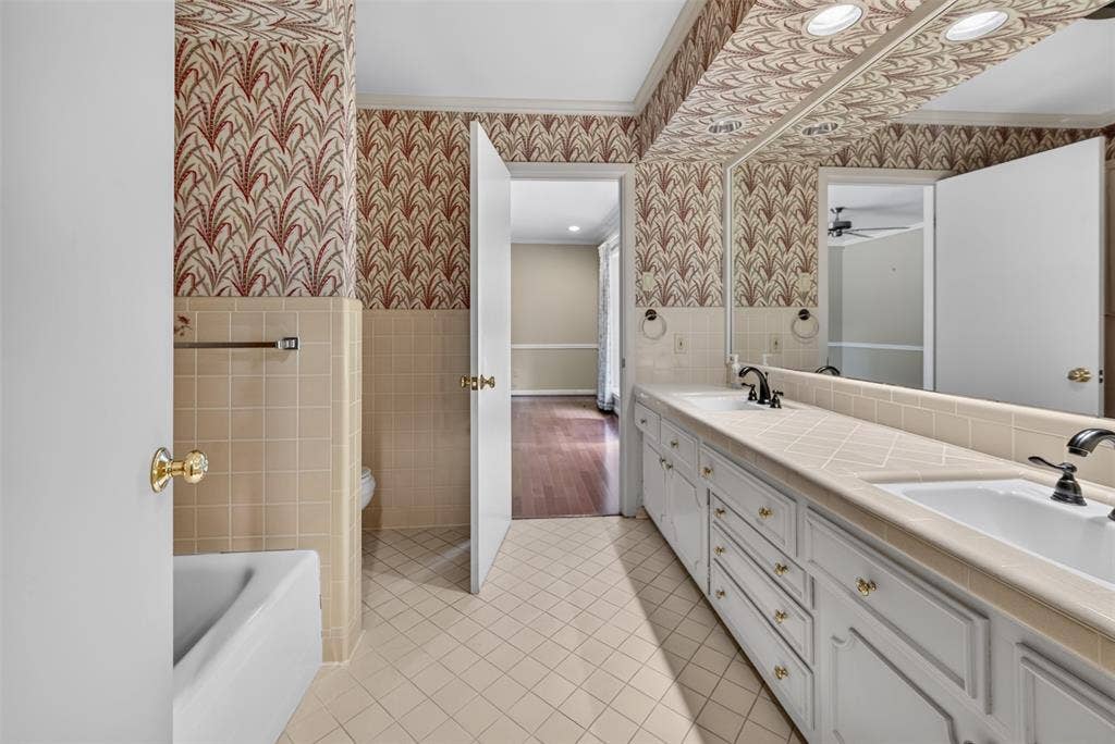 702 Mulberry Drive, Athens, TX 75751 Dual vanity with integrated sinks, extensive countertop space, white cabinetry with brass-tone hardware, and a full-width mirror