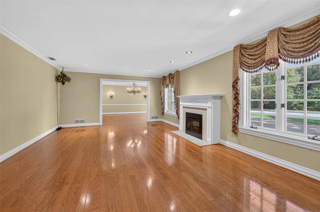 702 Mulberry Drive, Athens, TX 75751 Hardwood flooring, recessed lighting, white mantel fireplace with stone surround, large windows, and crown molding