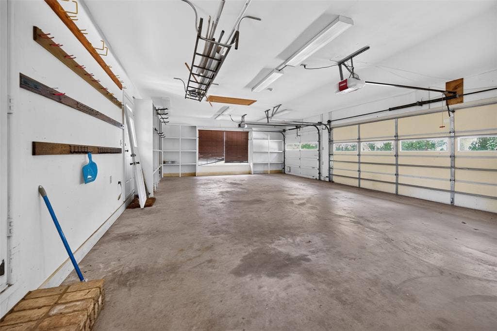 702 Mulberry Drive, Athens, TX 75751 Spacious garage featuring a concrete floor, two overhead doors with window panels, built-in shelving, and bright overhead lighting