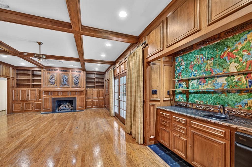 702 Mulberry Drive, Athens, TX 75751 Hardwood flooring, wood-paneled walls, built-in shelving, fireplace, and a built-in wet bar with a granite countertop