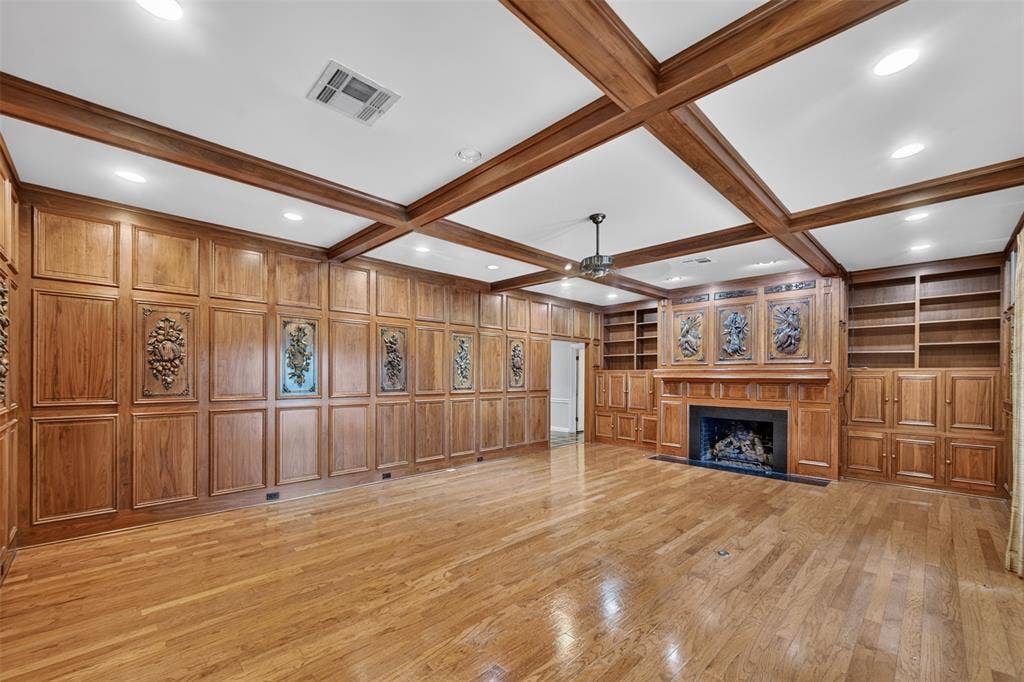 702 Mulberry Drive, Athens, TX 75751 Wood-paneled room featuring a coffered ceiling, a fireplace with a stone surround, built-in shelving, and wood flooring