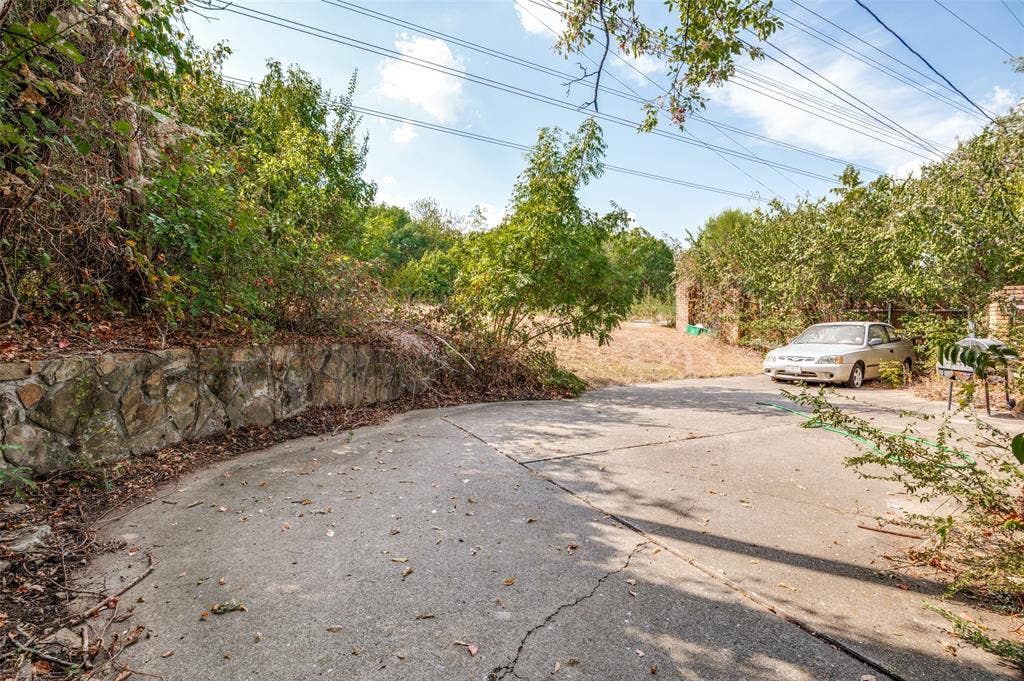1901 Wedgewood Drive, Grand Prairie, TX 75050 Stone retaining wall with established trees and foliage