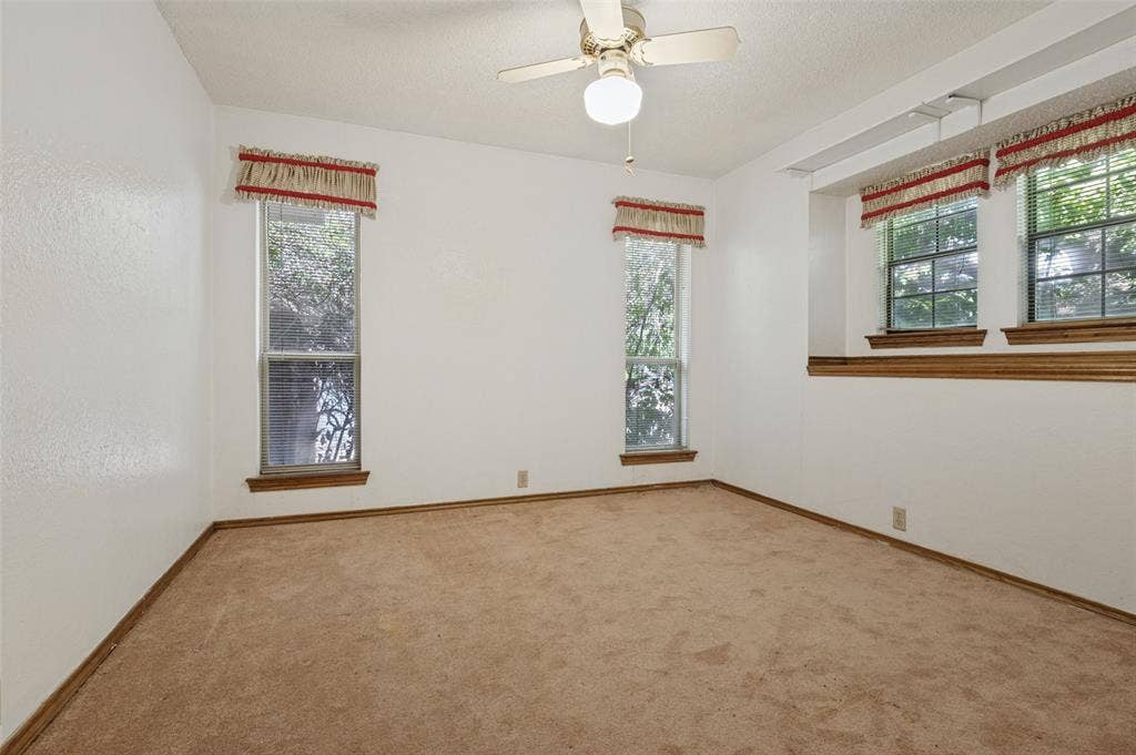 1901 Wedgewood Drive, Grand Prairie, TX 75050 Neutral wall finish with a textured surface, multiple windows, built-in wooden trim, and a ceiling fan with integrated lighting