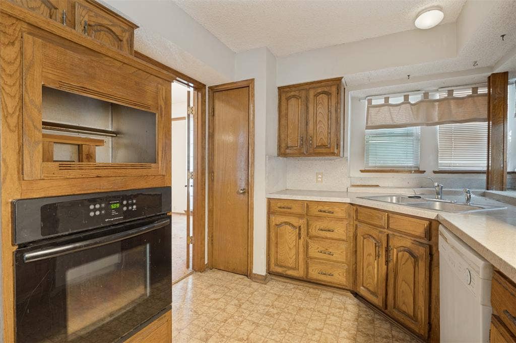 1901 Wedgewood Drive, Grand Prairie, TX 75050 Hardwood-finish cabinetry, built-in wall oven, double basin sink, light-toned countertops, and patterned flooring