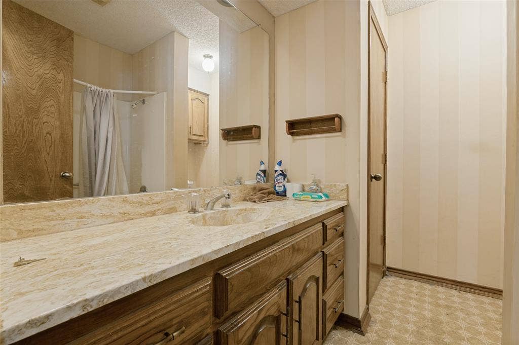 1901 Wedgewood Drive, Grand Prairie, TX 75050 Vanity with a polished stone countertop, integrated sink, and wood-finish cabinetry