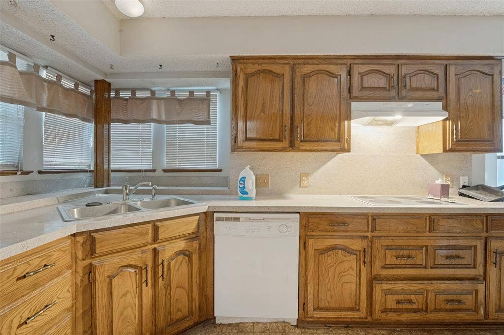 1901 Wedgewood Drive, Grand Prairie, TX 75050 Kitchen featuring wood cabinetry, light-toned countertops, a double basin sink, and a built-in dishwasher