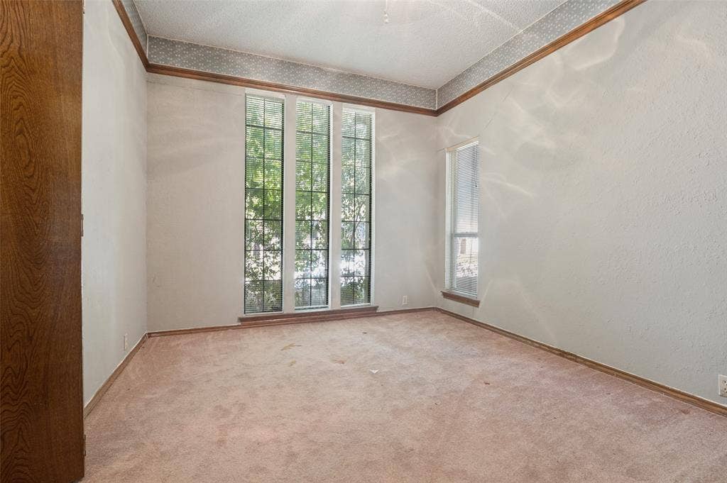 1901 Wedgewood Drive, Grand Prairie, TX 75050 Expansive room featuring multiple windows, a wood door, and wood trim detailing