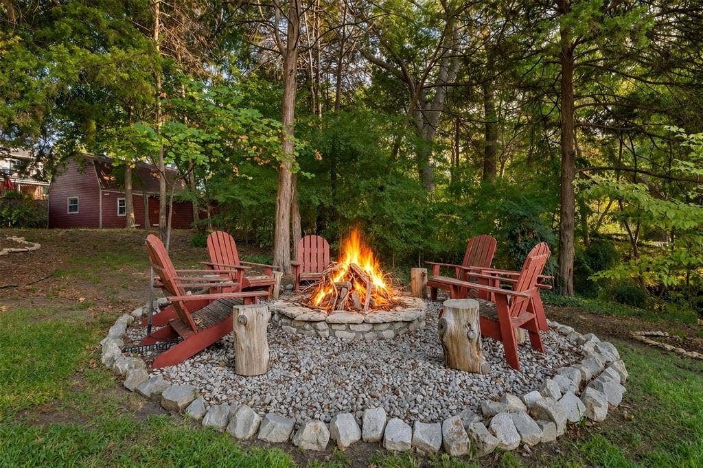 3202 Harbor Pointe Drive, Rowlett, TX 75088 Stone-bordered fire pit with gravel ground cover, surrounded by mature trees